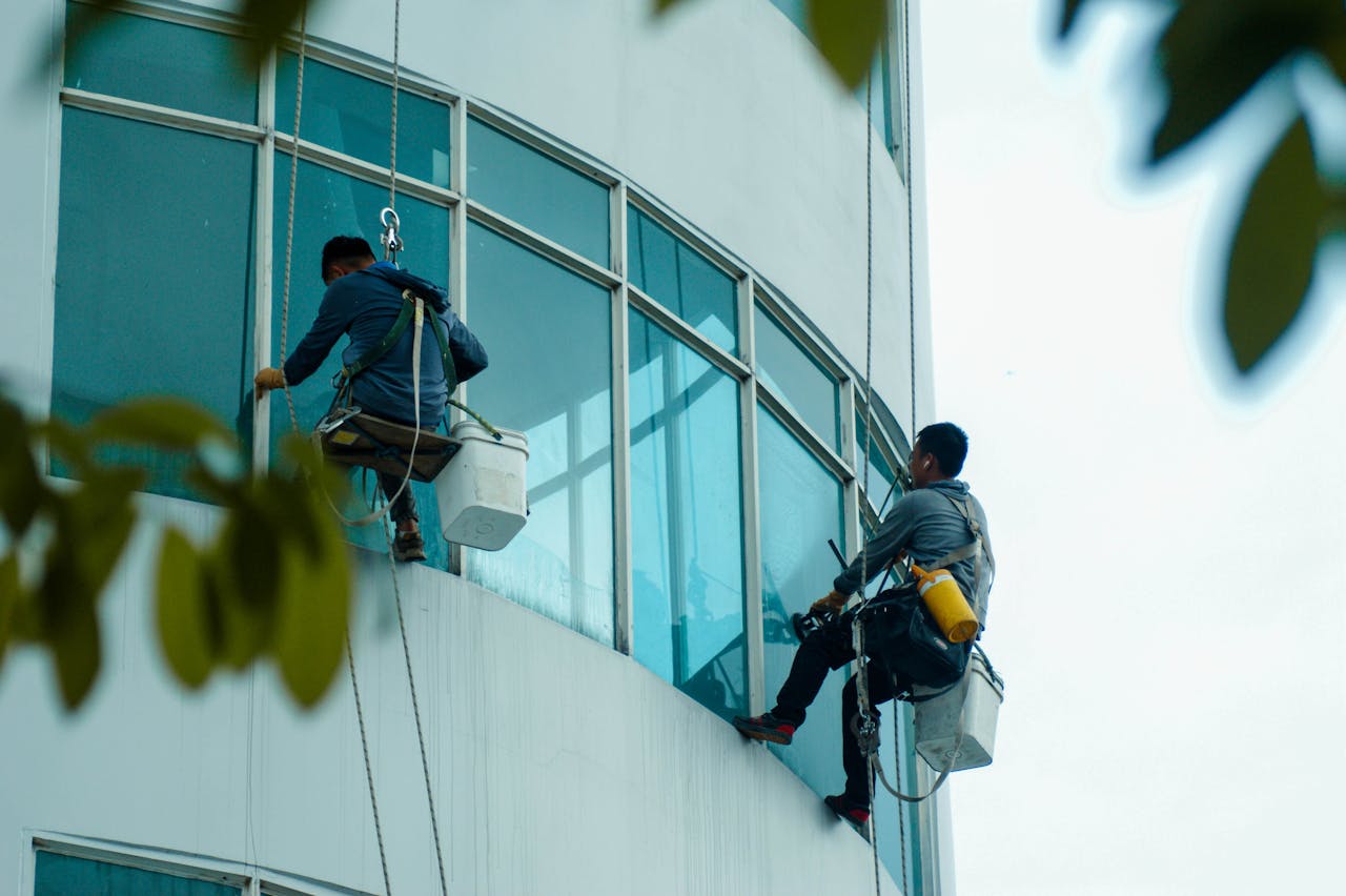 services-03 Window cleaners suspended on ropes clean a high-rise buildings glass exterior.